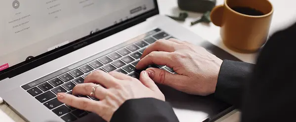 Händer som skriver på ett tangentbord på en laptop.